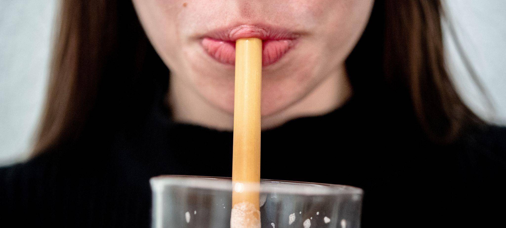 Eine junge Frau trinkt durch einen Trinkhalm aus Bambus