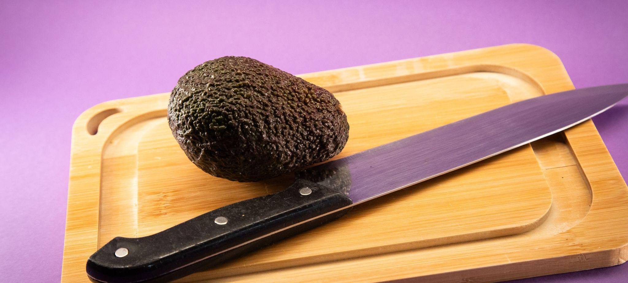 Eine Avocado liegt auf einem Holzbrett